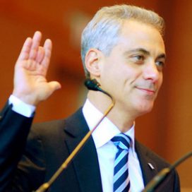 Rahm Emmanuel's missing finger is really the top half of his middle finger, cut off between the second and third knuckle. He stands in a blue suit and tie, surrounded by family, as he raises his hand to take the oath of office.